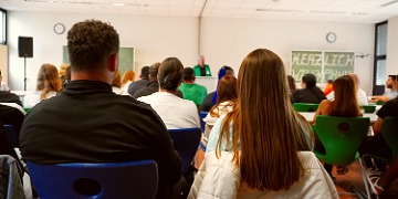 Auftaktveranstaltung Pflegeausbildung Personen auf Stühlen sitzend von hinten fotografiert bei einer Veranstaltung