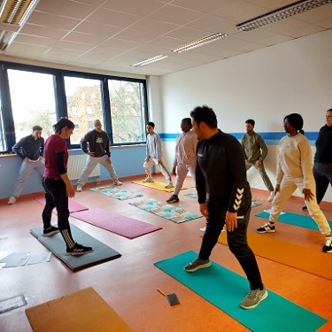 Eine Physiotherapeutin gibt den Schülern Übungen vor.